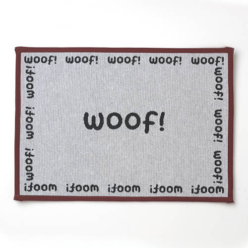 A dog mat with the word woof written in black lettering.