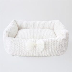 A white dog bed with a bow on it.