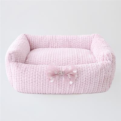 A pink dog bed with a bow on it.