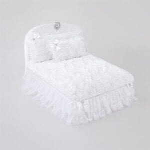 A bed with white ruffles and pillows on it.