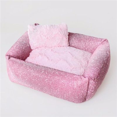 A pink dog bed with pillows on top of it.